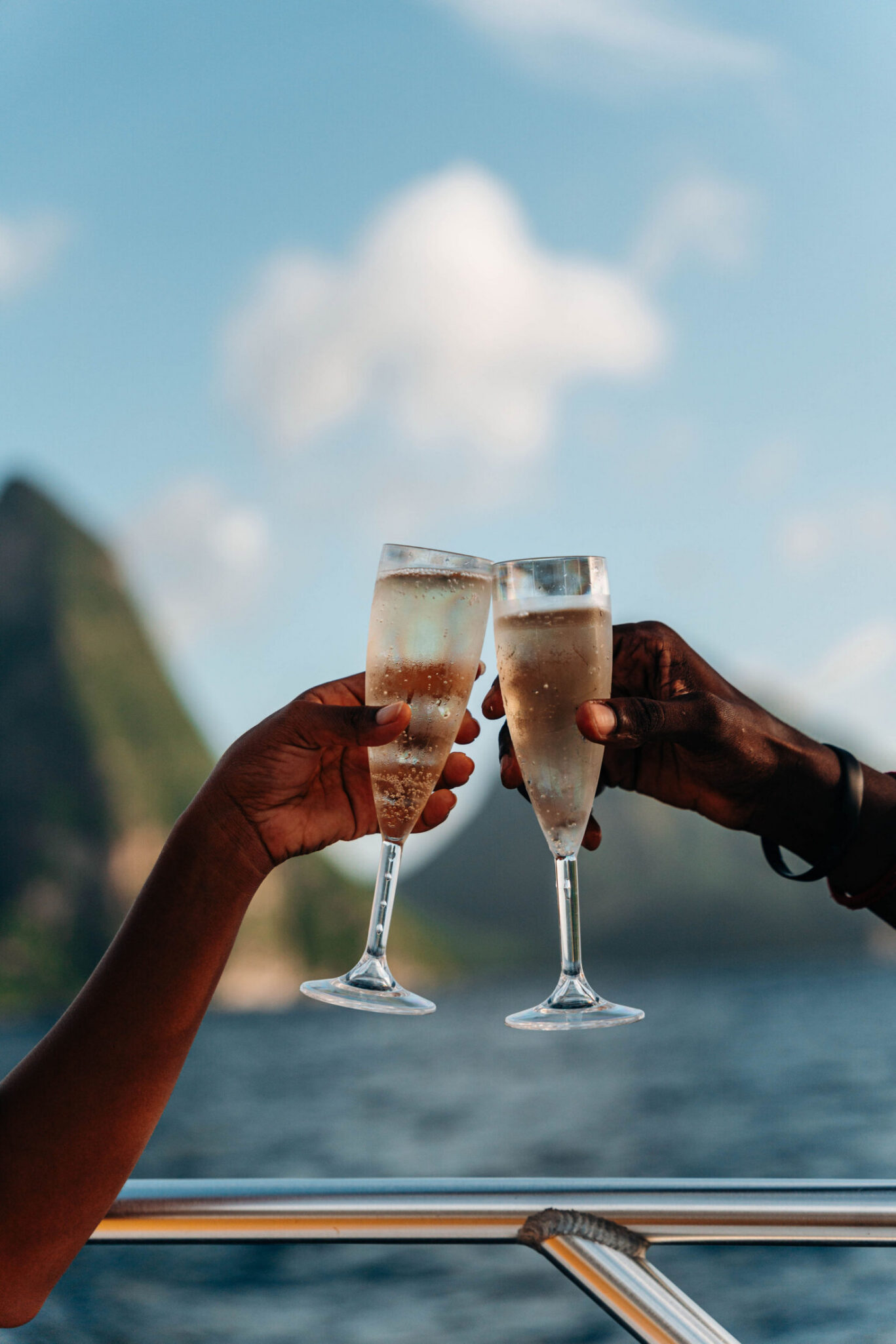 Two flutes of Champagne in a toast with the ocean in the background