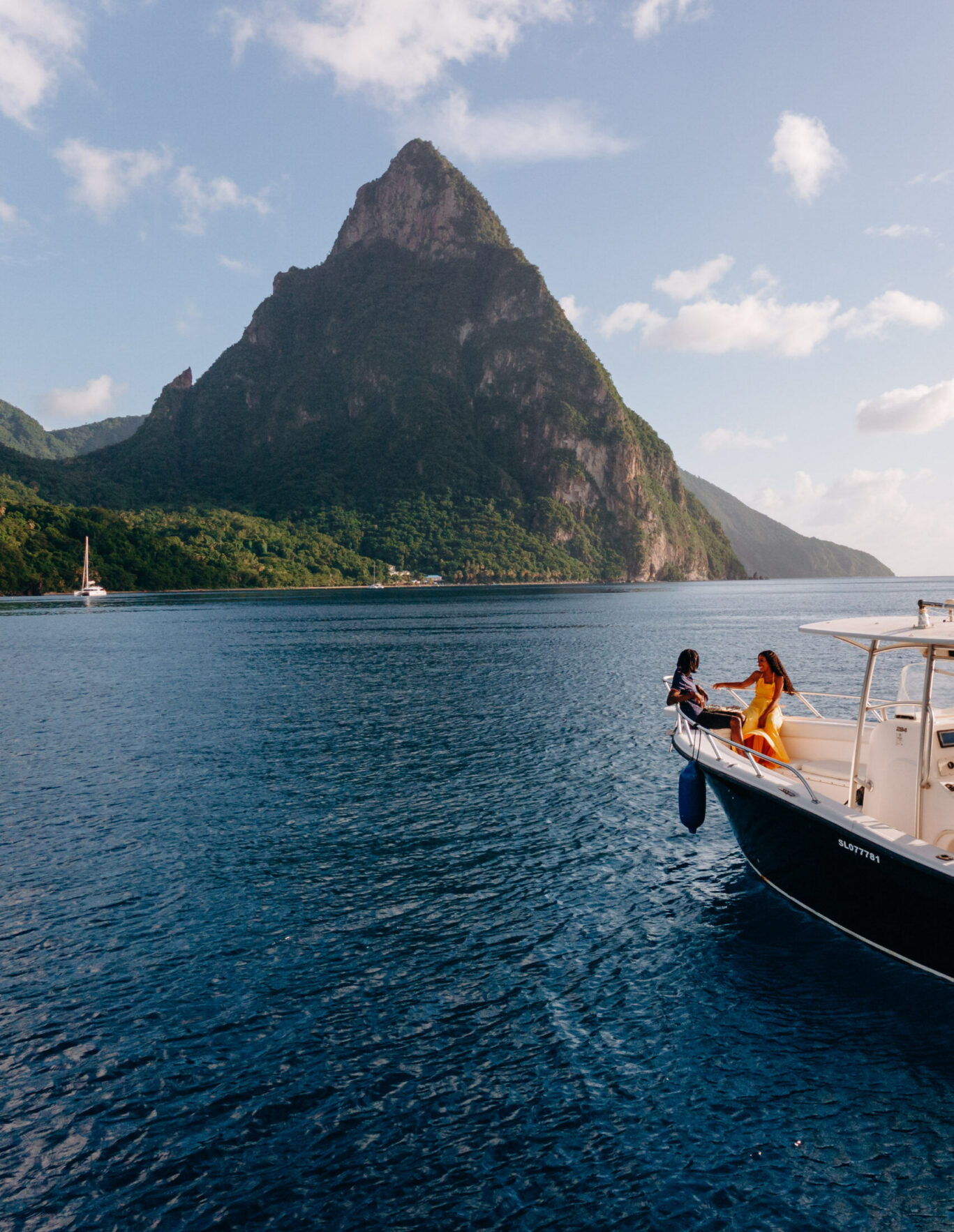 A couple enjoy a sunset cruise on a boat with the Petit Piton in the background